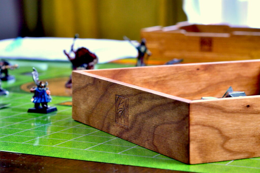 Cherry Artisan Dice tray on a game tabletop with miniatures in the background